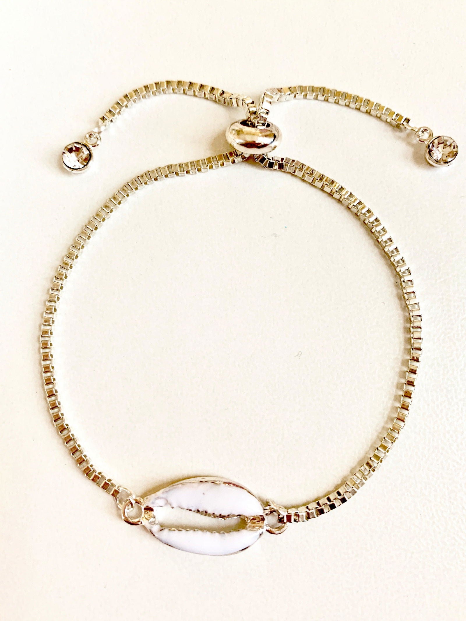 Silver seashell bracelet with beaded chain, oval shell charm, and three crystal details