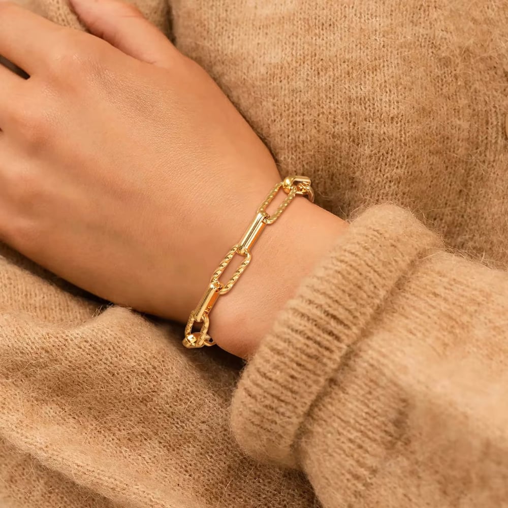 Gold paperclip chain bracelet stacked on wrist with adjustable clasp