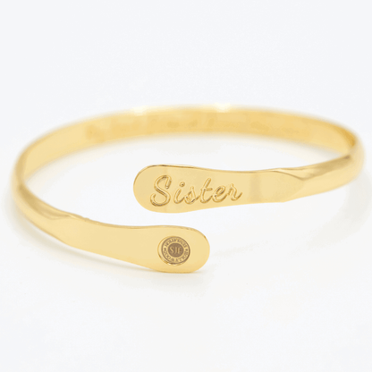 Gold sister engraved cuff bracelet with oval nameplate and round emblem