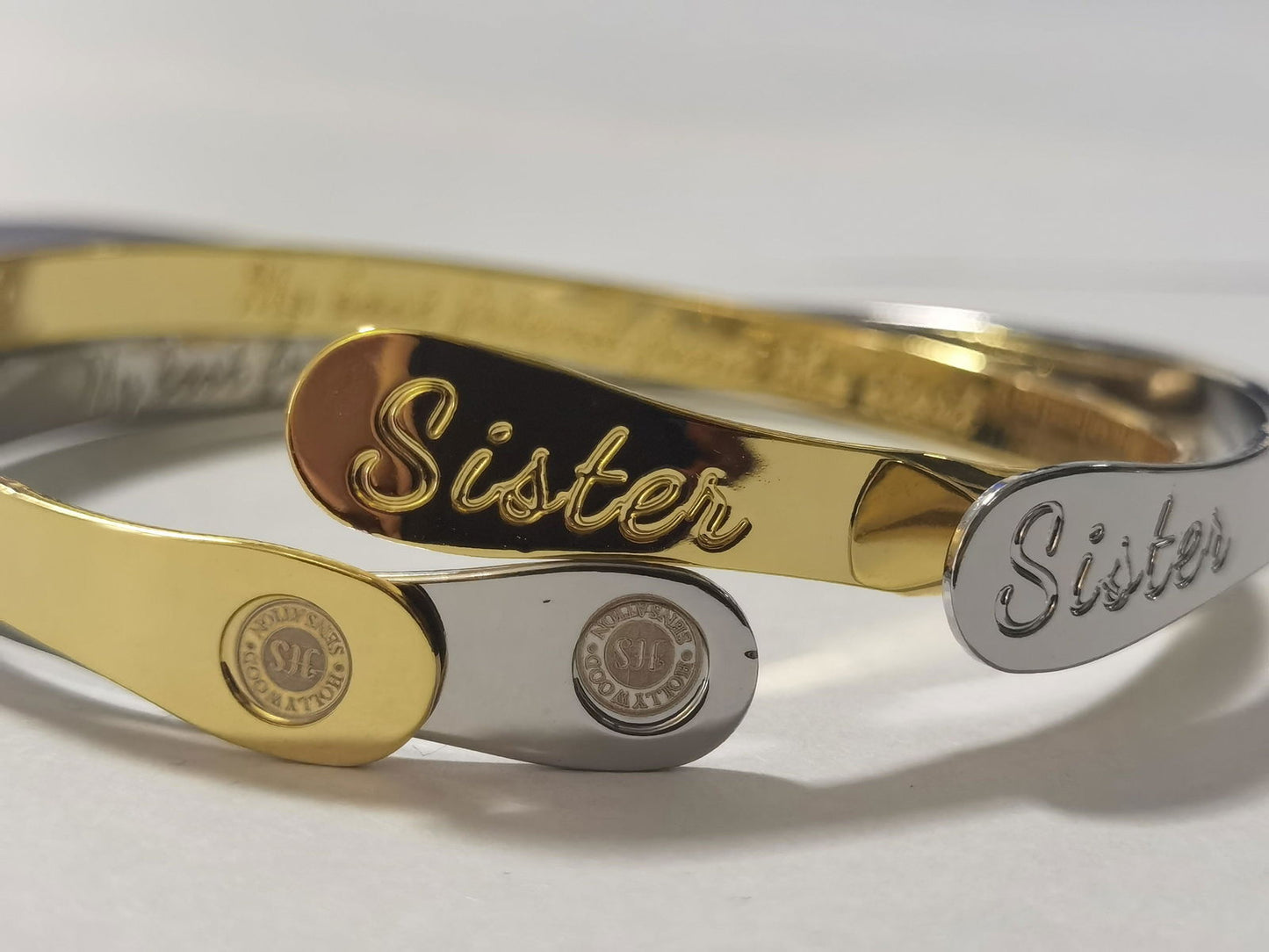 Stacked sister bracelets in gold and silver with engraved nameplates