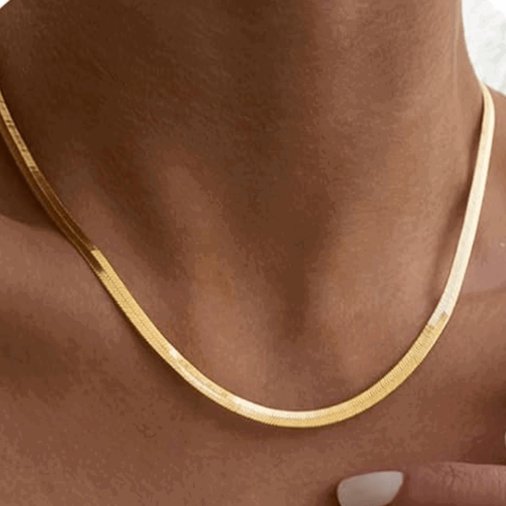 Gold snake chain necklace on neck, close-up of thin curved chain