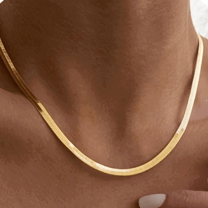 Gold snake chain necklace on neck, close-up of thin curved chain