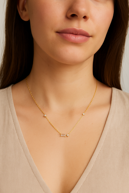 Gold tone cubic zirconia necklace on model skin: emerald-cut center with round side stones