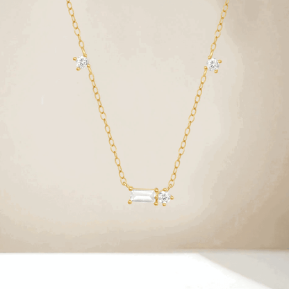 Gold tone cubic zirconia necklace with three round stones and a central emerald-cut charm