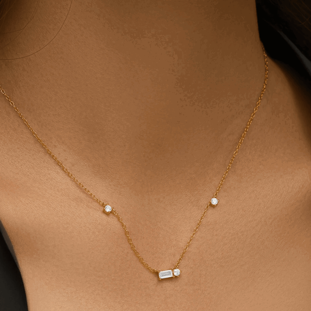 Gold tone necklace with small round stones and an emerald-cut cubic zirconia center charm