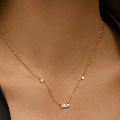 Gold tone necklace with small round stones and an emerald-cut cubic zirconia center charm
