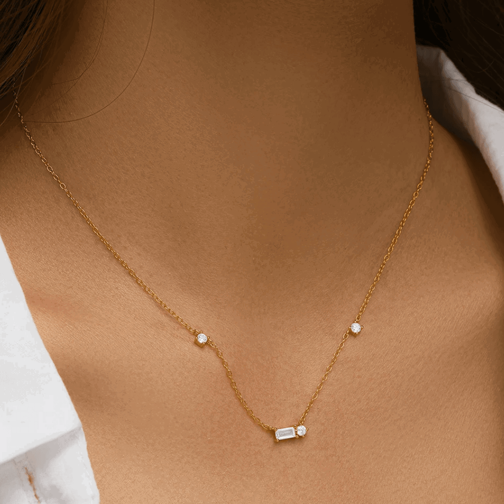 Gold tone necklace featuring round cubic zirconia stones and an emerald-cut center charm