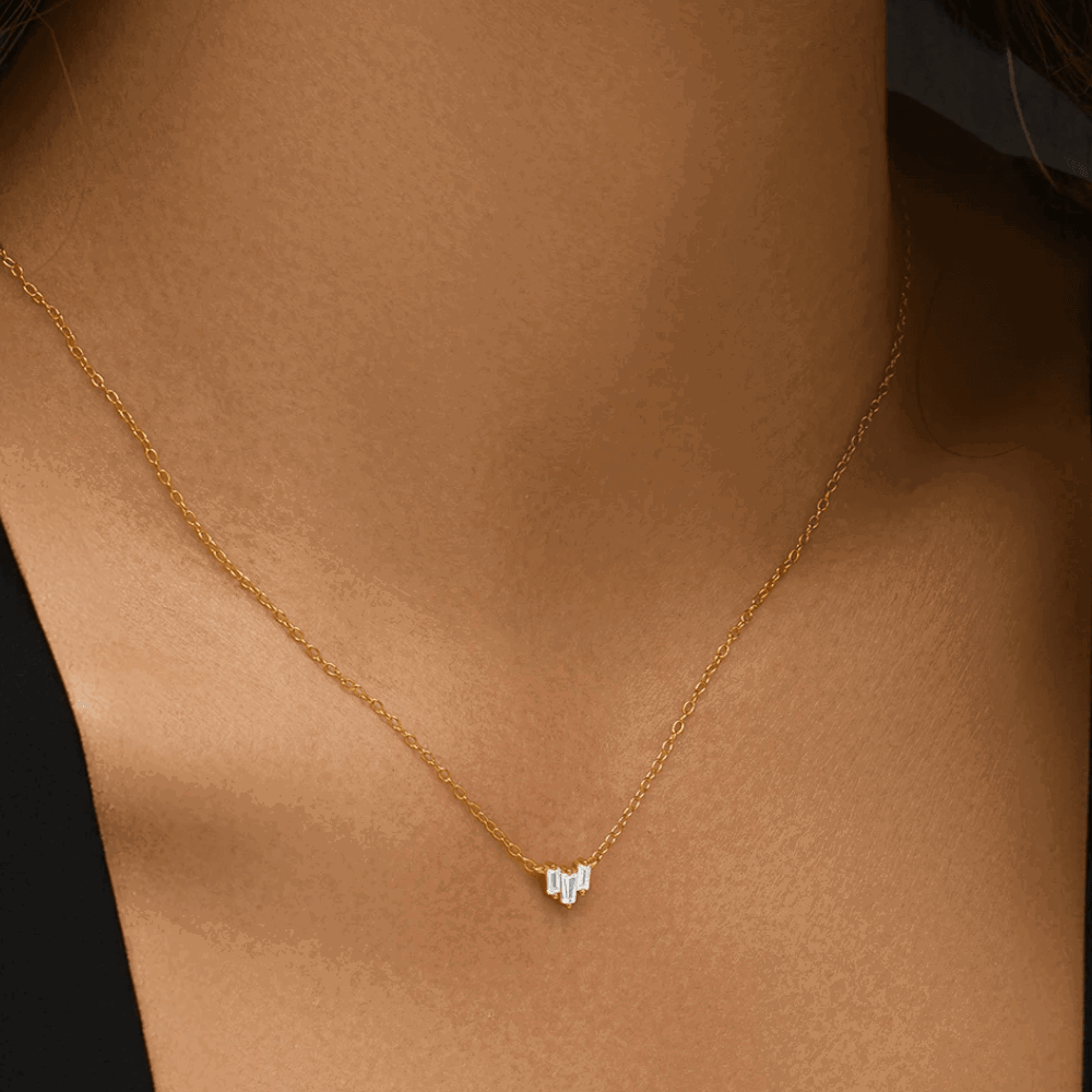 Gold-tone necklace on neckline, three emerald-cut cubic zirconia stones in V pendant