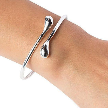 Silver teardrop cuff bracelet on wrist with curved open teardrop charm