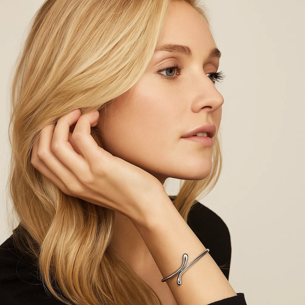 Silver teardrop cuff bracelet on arm, minimal curved bangle with teardrop mark