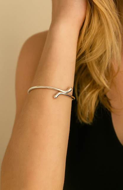 Silver teardrop cuff bracelet on wrist, slim bangle with open teardrop shape