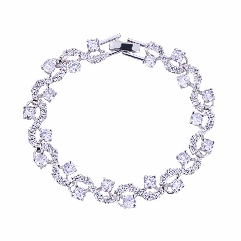 Round-cut cubic zirconia tennis bracelet in silver-tone, flexible oval link design.