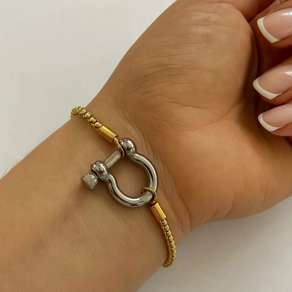 Two-tone bracelet on wrist: silver horseshoe carabiner clasp with gold beaded chain.