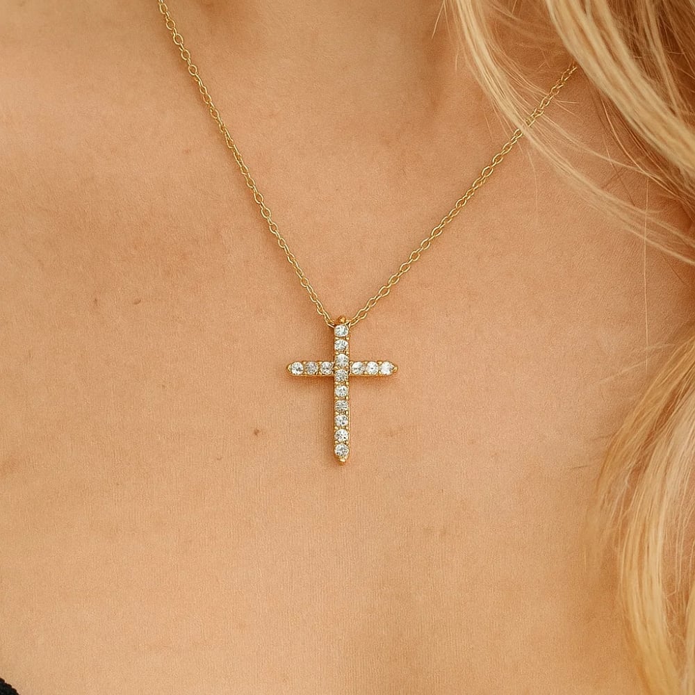 Gold-tone cross pendant necklace with clear CZ stone details, close-up on skin