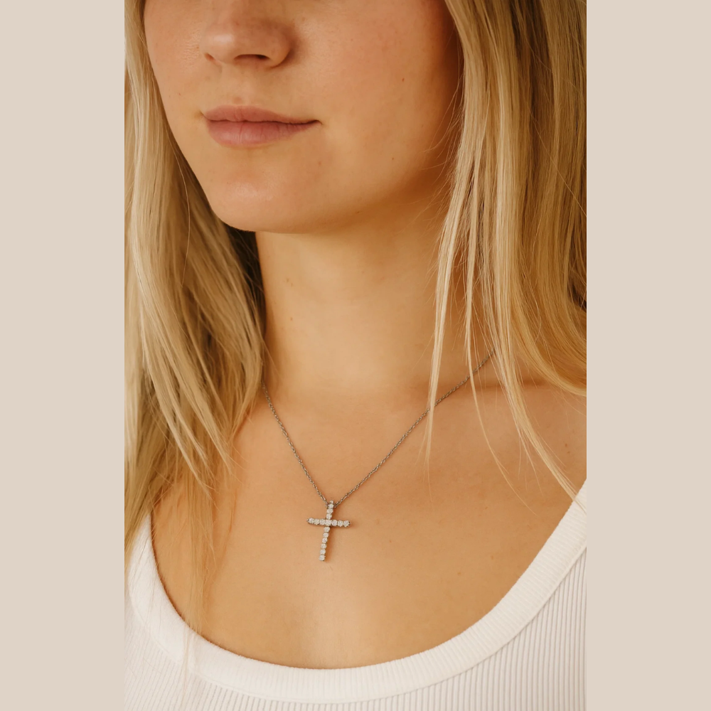 Silver-tone cross pendant necklace with clear CZ stones, worn on chest