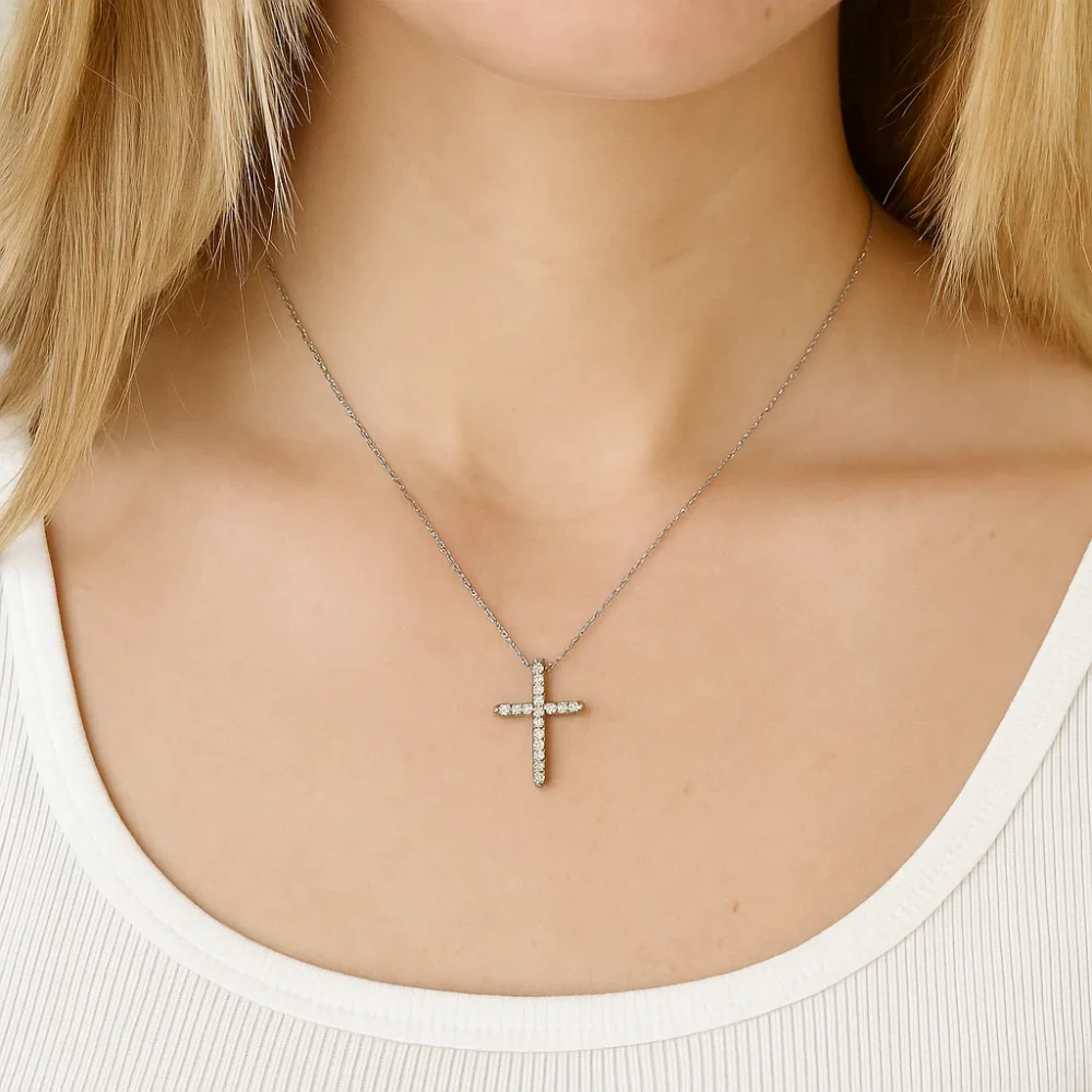 Silver-tone cross pendant necklace with clear CZ stones, worn on neckline