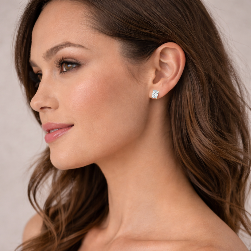 Emerald-cut moissanite stud earrings in silver-tone metal, square stones on ear