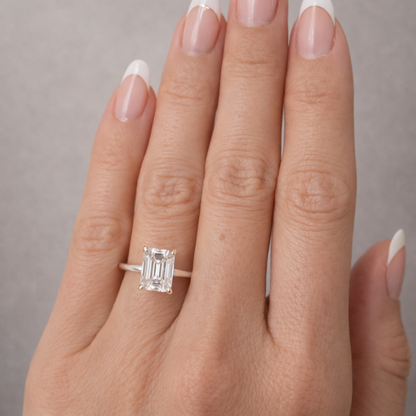 Emerald-cut solitaire ring with clear square center stone and four prongs on silver-tone band