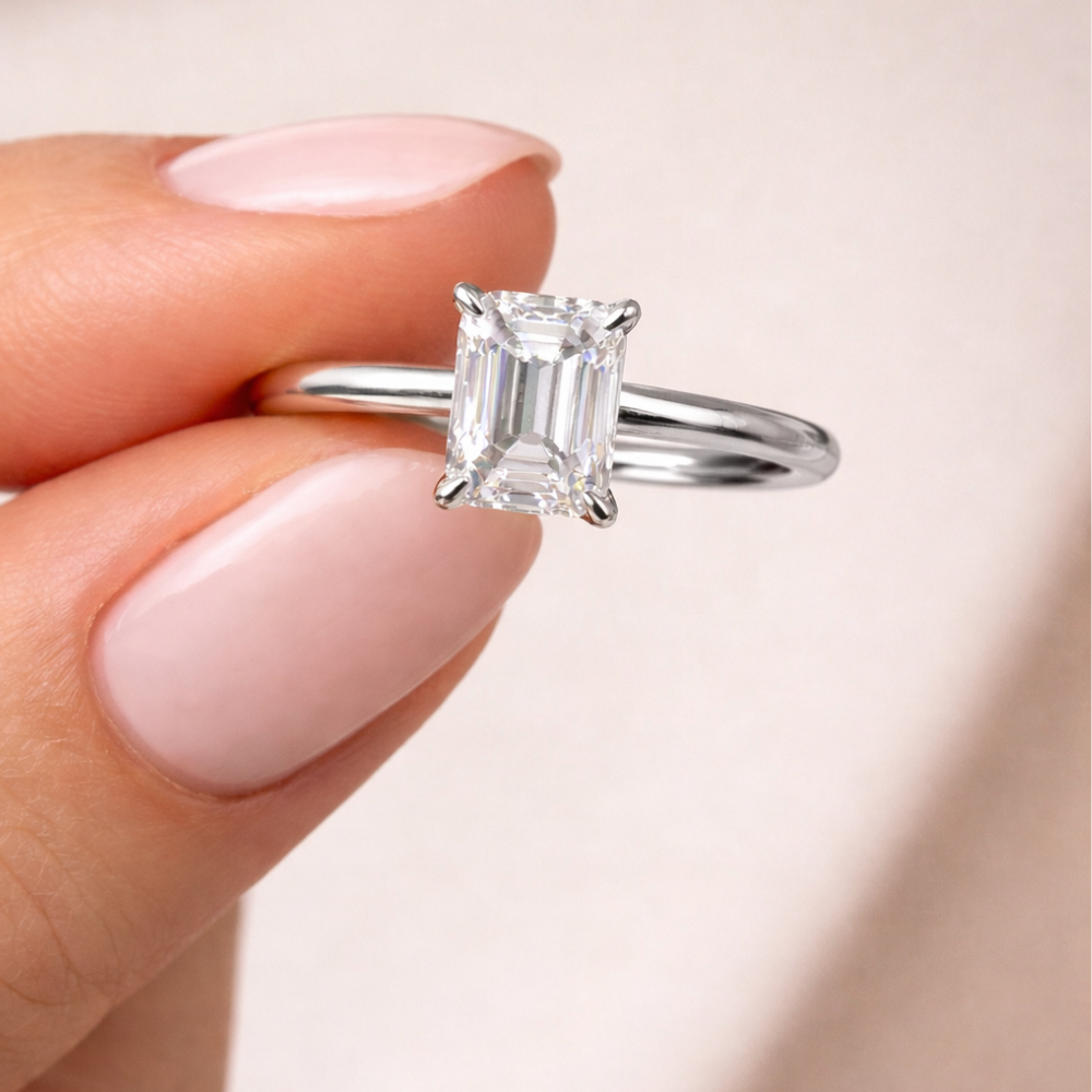Emerald-cut solitaire ring with clear square stone and four-prong setting on silver-tone band