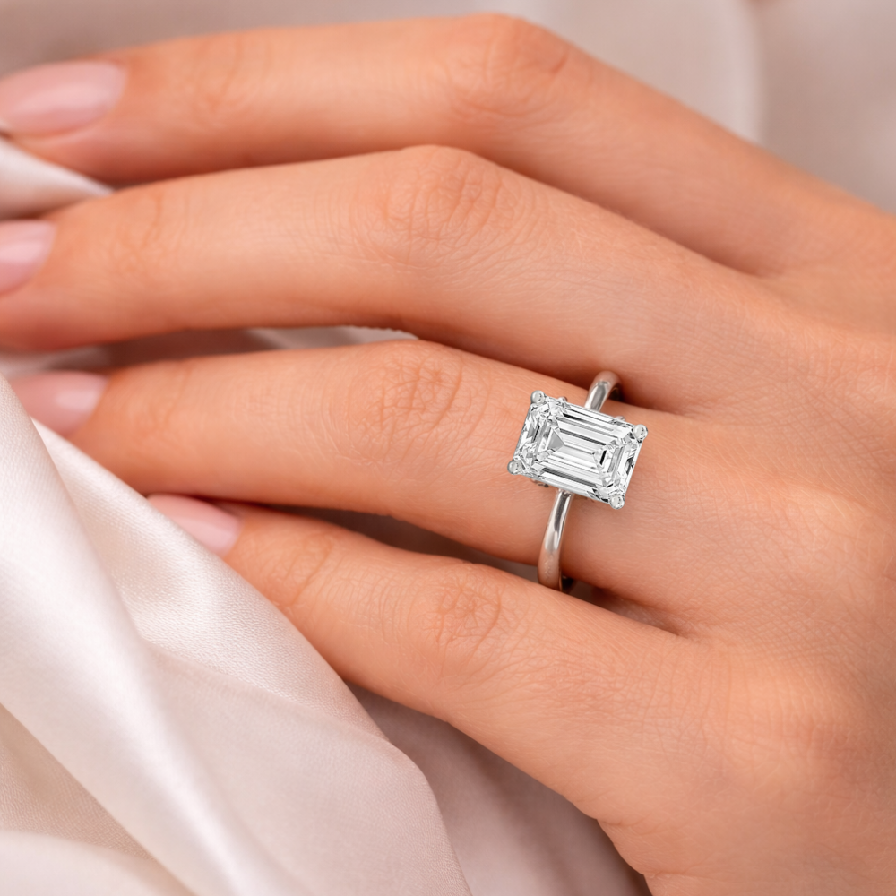 Emerald-cut solitaire ring with clear square stone, four-prong setting on silver-tone band
