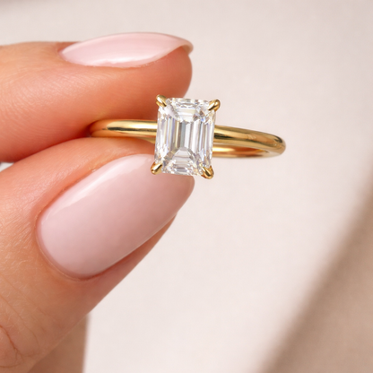 Gold vermeil emerald-cut solitaire ring with raised center stone on finger
