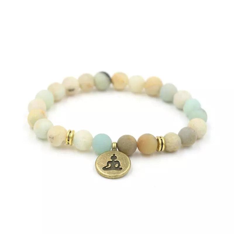 Beige and light blue stone bead bracelet with small gold accents and round gold Buddha charm.