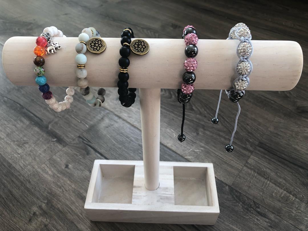 Beaded spiritual charm bracelets on a display stand in black and assorted colors