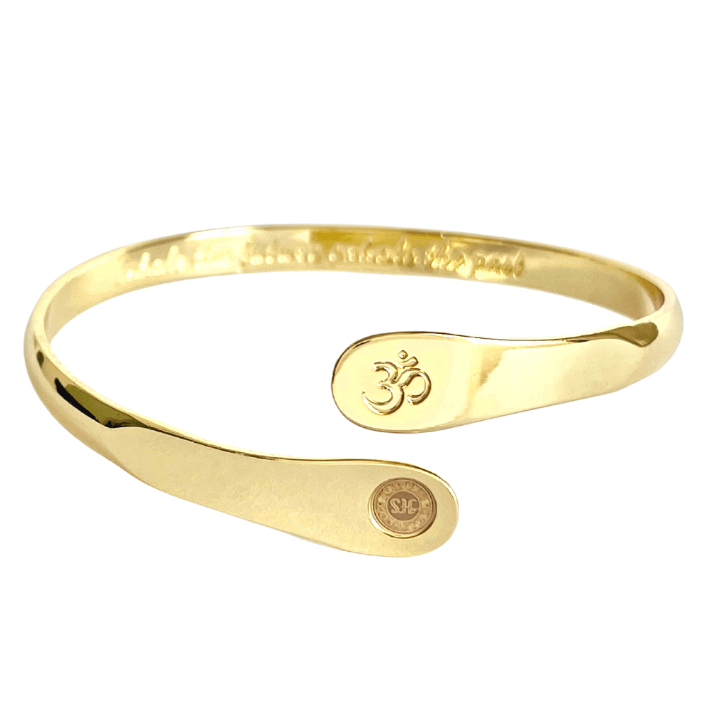 Gold yoga bracelet with raised Om engraving and two round stamped discs