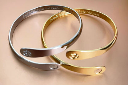 Silver and gold yoga bracelets laid together, each with engraved Om and round side logo