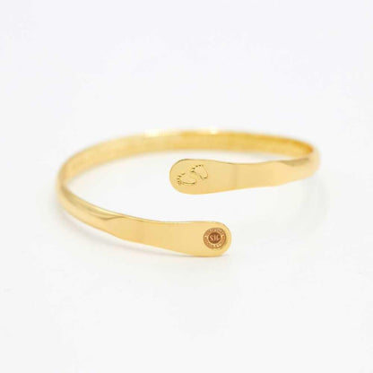 Gold baby footprint engraved bangle bracelet with oval footprint charm and small round logo.