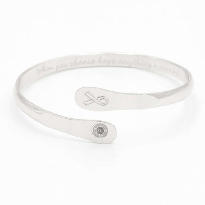 Silver awareness bracelet with ribbon charm and round medallion, engraved message inside