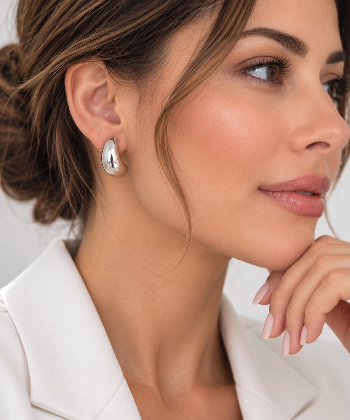 Silver dome huggie teardrop hoop earrings on model’s ear