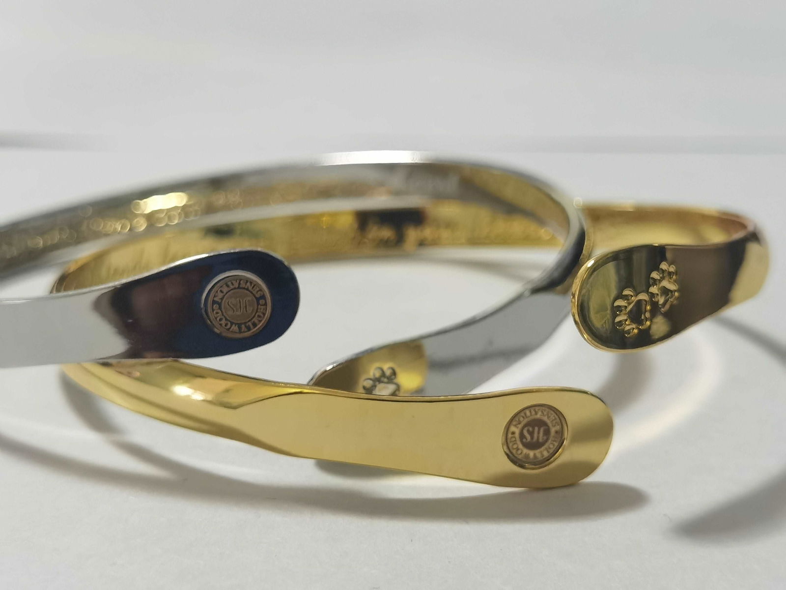 Gold and silver cuff bracelets with oval medallion and paw print details