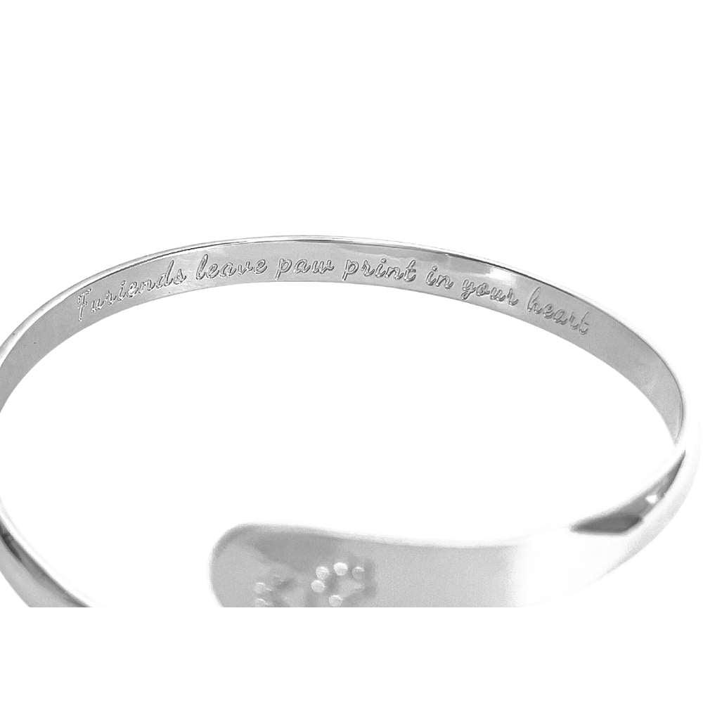 Silver cuff bracelet with paw print engraving on inner plate and logo medallion